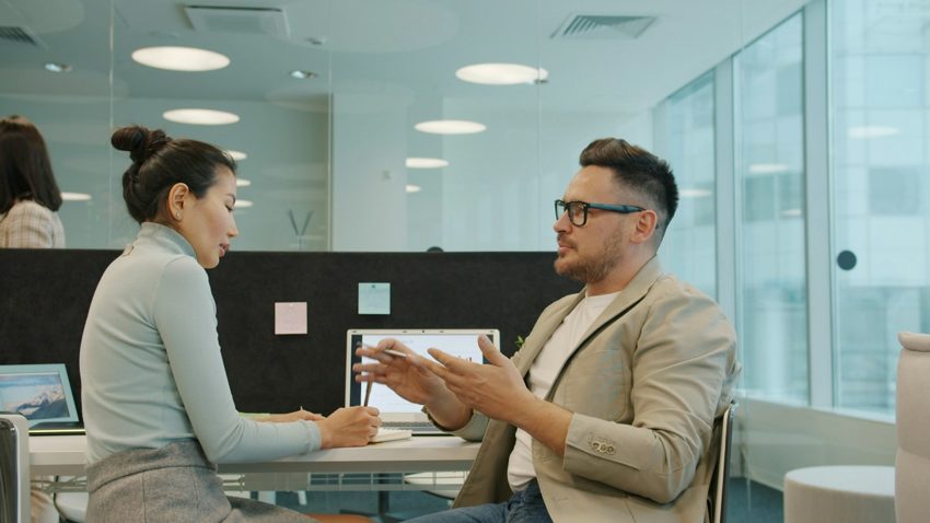 Colleagues discussing work in an office; illustrative stock photography.